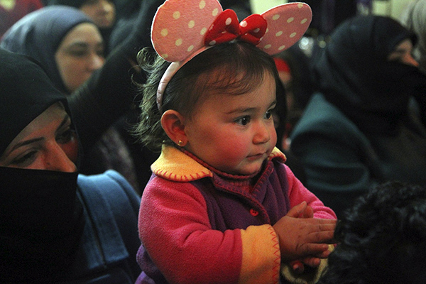 A woman carries her daughter during the opening of an underground centre for children in Aleppo, Syria, on Thursday (Reuters photo)